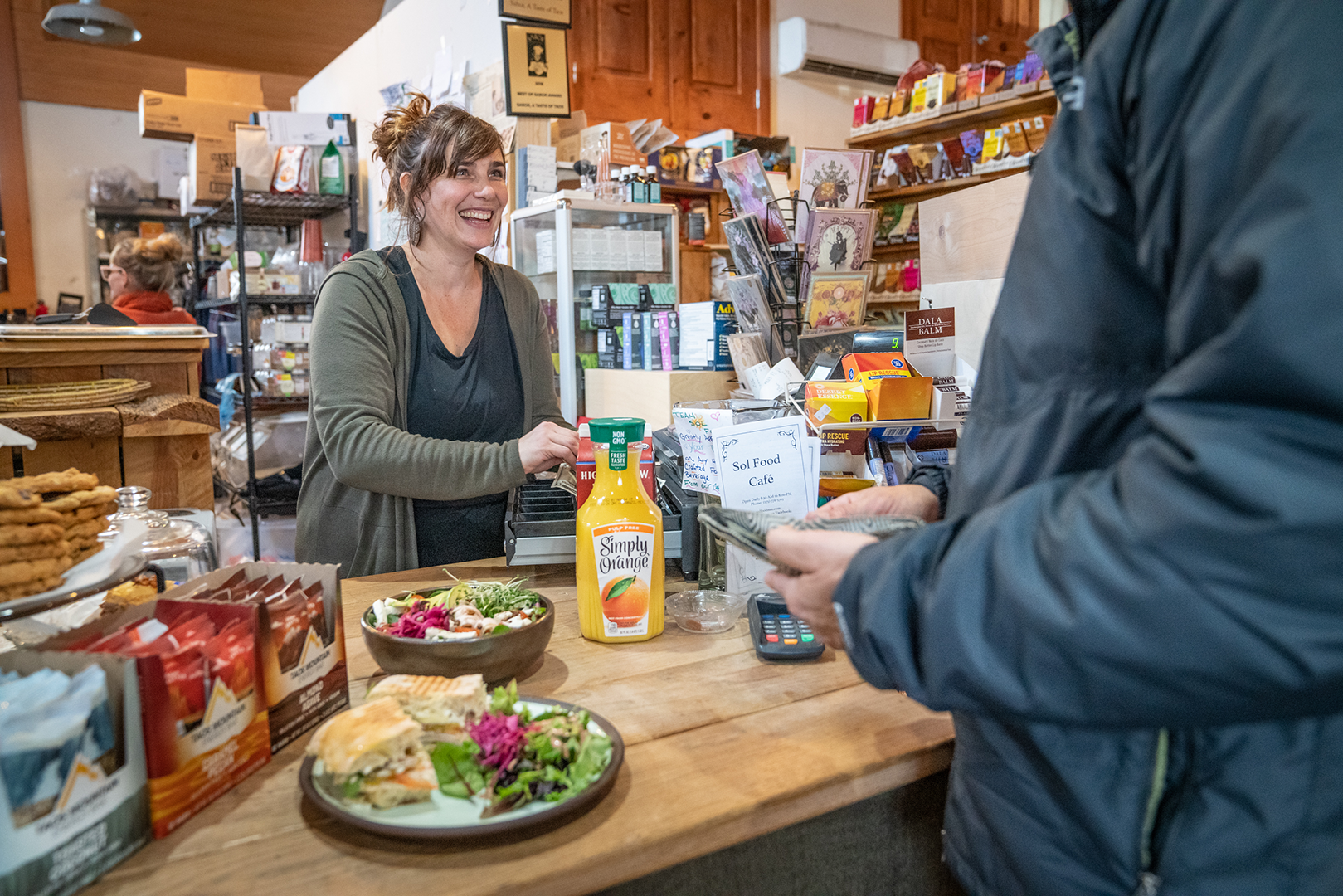 Woman at retail counter ordering lunch with Taos Bakes granola bars